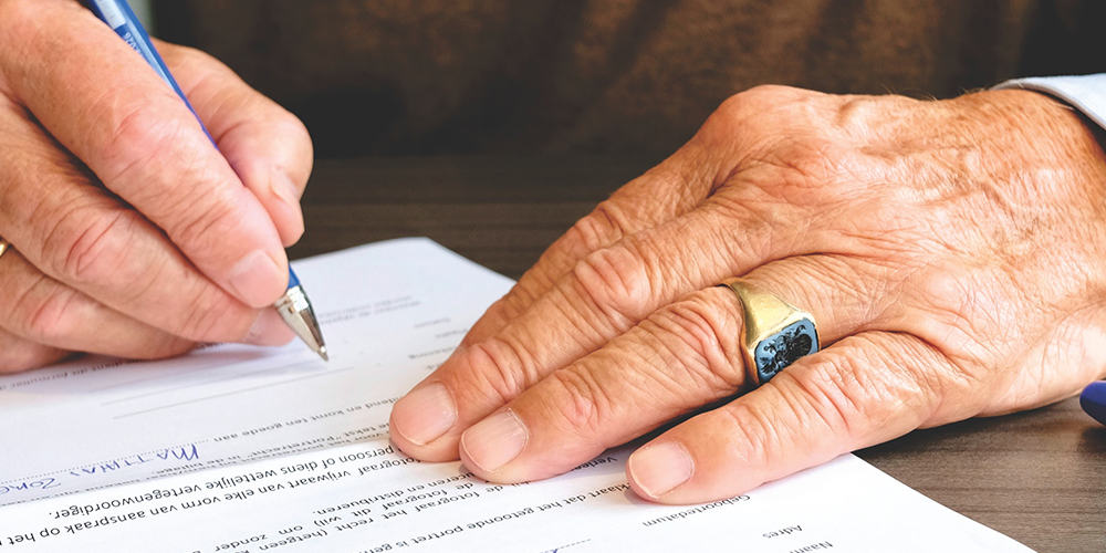 Mains de personnes âgée signant un contrat